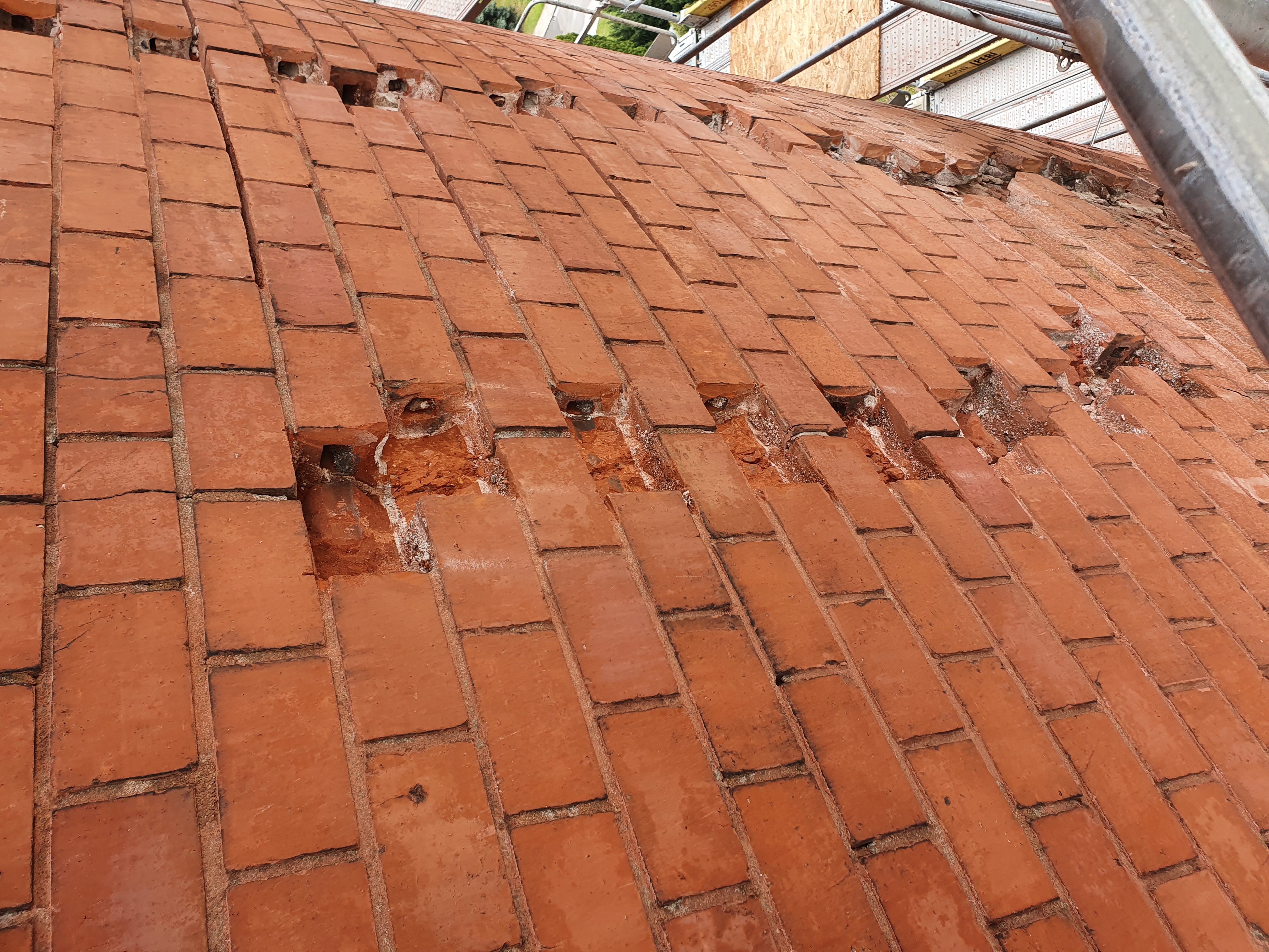 ubytki i pęknięcia na powierzchni ceglanej ściany wieży ciśnień